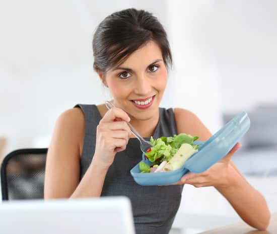 Businesswoman eating from lunch box in office