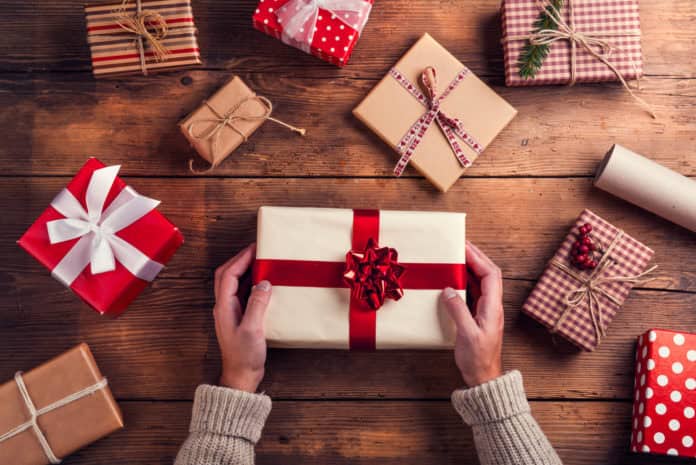 stock-photo-man-holding-christmas-presents-laid-on-a-wooden-table-background-331719365