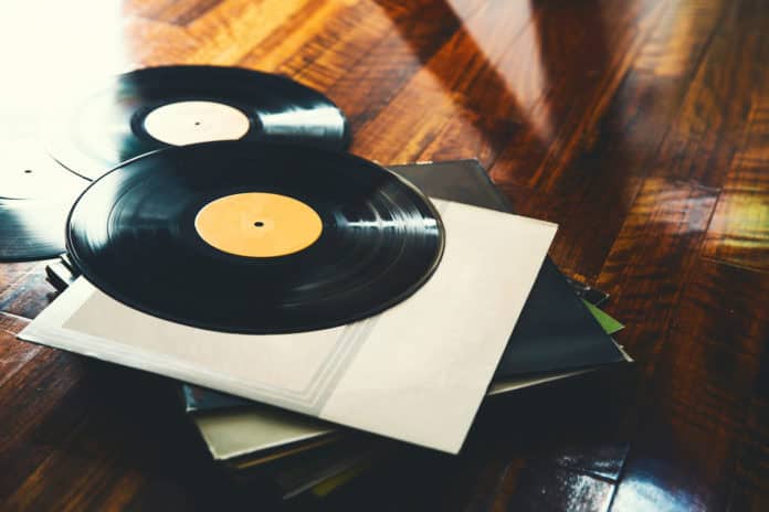 Old vinyl record and a collection of albums on wooden background